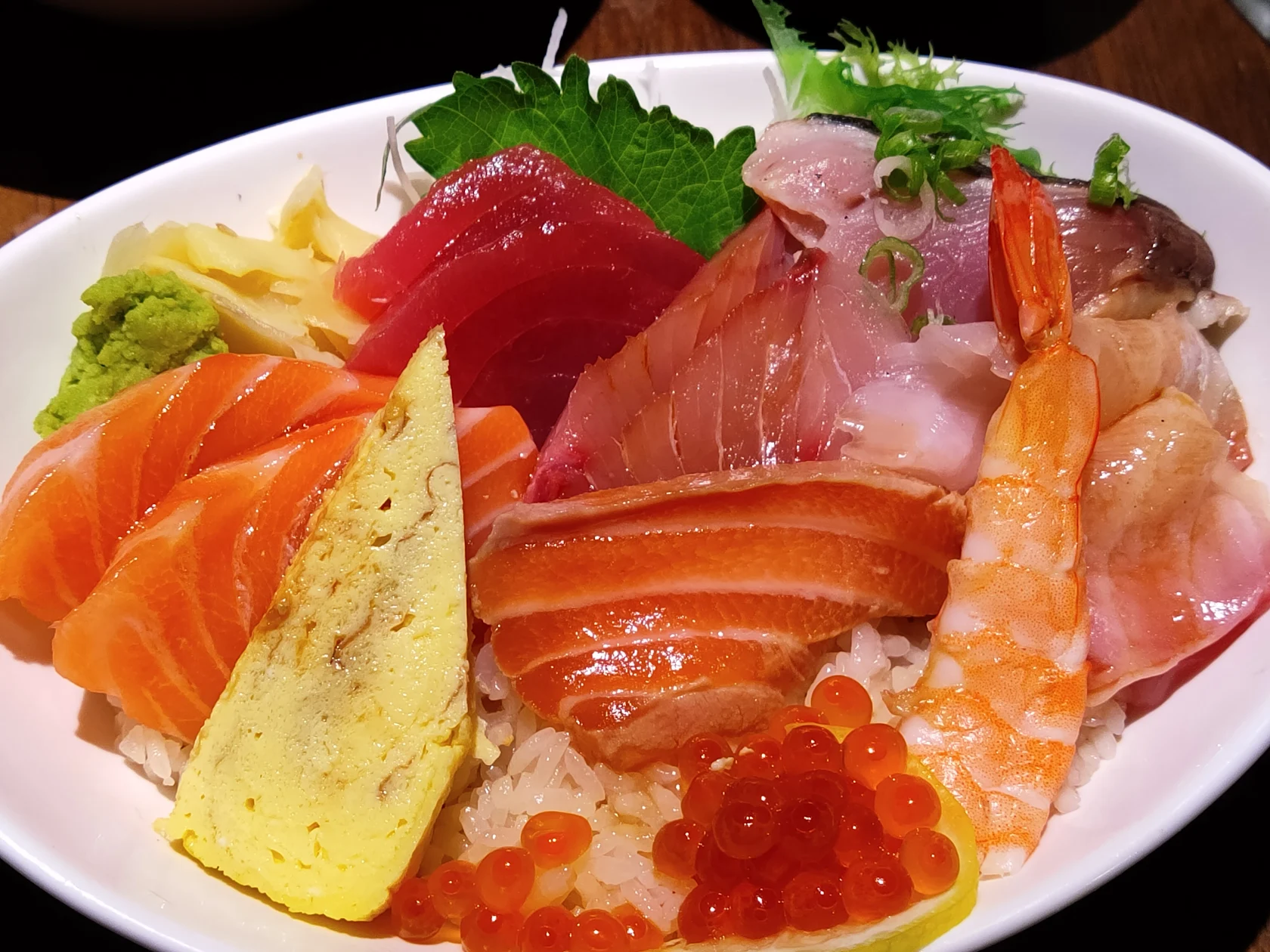 A bowl of chirashi piled with salmon, tuna, shrimp, ikura and tamago