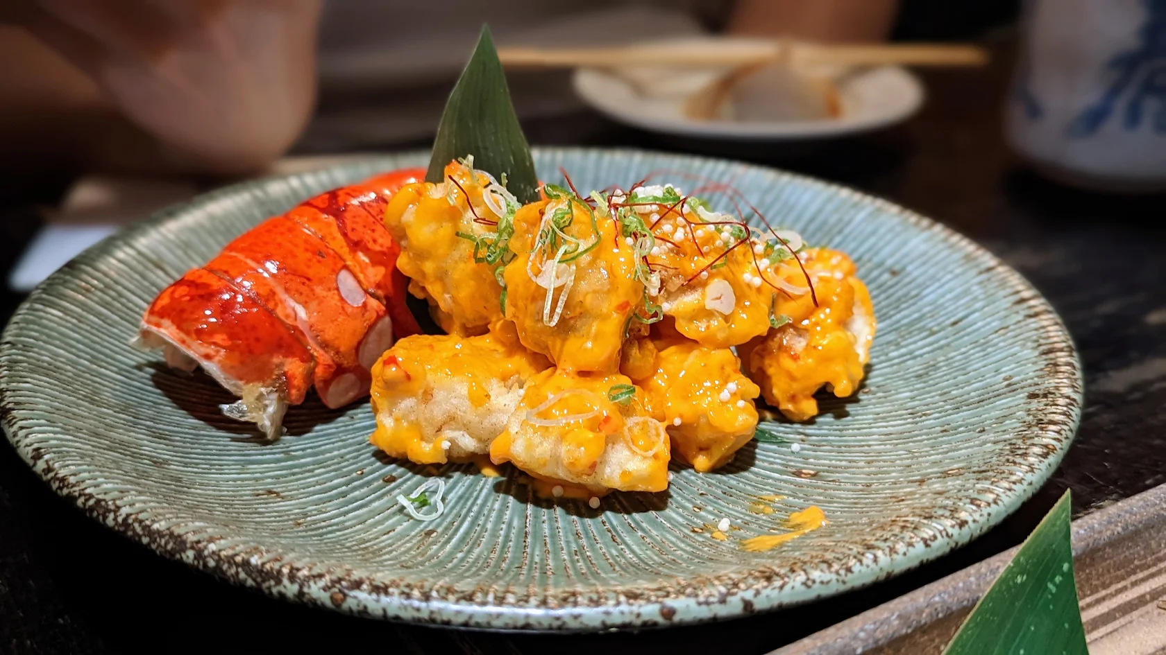 Lobster balls with spicy mayo and a lobster tail on a blue glazed plate