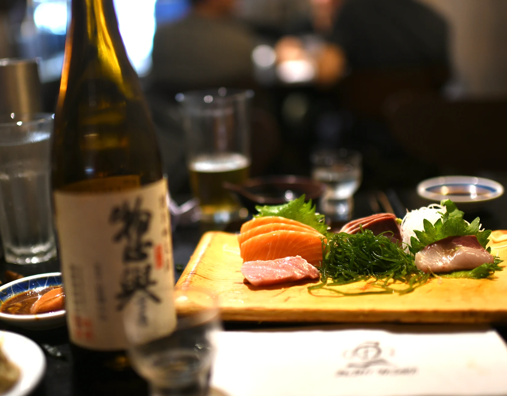 A sashimi board beside a bottle of sake
